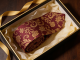 The Buckingham Wine Floral Silk Tie rolled in a gift box, close detail of the silk weave