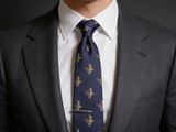 The Windsor Mallard Silk Tie worn in a four-in-hand knot with a white collar and charcoal suit