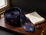 The Windsor Mallard Silk Tie coiled on dark walnut with a pocket square and brass collar bar