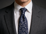 The Chelsea Vine Silk Tie worn in a four-in-hand knot with a white collar and charcoal suit