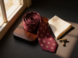 The Kingsway Heraldic Silk Tie coiled on dark walnut with a pocket square and brass collar bar