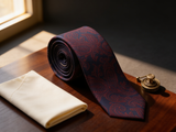 The Heritage Paisley Silk Tie coiled on dark walnut with a pocket square and brass collar bar
