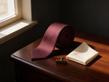 The Belgravia Micro-Diamond Silk Tie coiled on dark walnut with a pocket square and brass collar bar