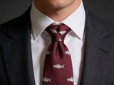 The Speyside Salmon Silk Tie worn in a four-in-hand knot with a white collar and charcoal suit