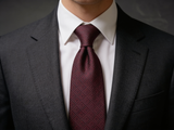 The Belgravia Micro-Diamond Silk Tie worn in a four-in-hand knot with a white collar and charcoal suit
