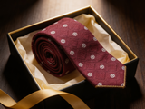 The Mayfair Burgundy Diamond Tie rolled in a gift box, close detail of the silk weave