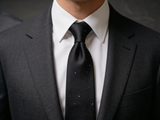 The Mayfair Charcoal Diamond Tie worn in a four-in-hand knot with a white collar and charcoal suit