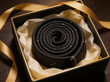 The Mayfair Charcoal Diamond Tie rolled in a gift box, close detail of the silk weave