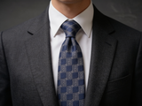 The Regent Silver Geometric Tie worn in a four-in-hand knot with a white collar and charcoal suit