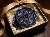 The Mayfair Navy Diamond Tie rolled in a gift box, close detail of the silk weave