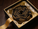 The Sovereign Gold Paisley Tie rolled in a gift box, close detail of the silk weave