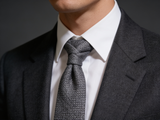 The Bond Textured Grenadine Tie worn in a four-in-hand knot with a white collar and charcoal suit