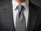 The Regent Geometric Diamond Tie worn in a four-in-hand knot with a white collar and charcoal suit