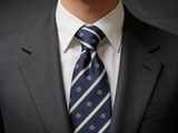 The Mayfair Club Stripe Tie worn in a four-in-hand knot with a white collar and charcoal suit