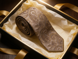 The Belgravia Taupe Paisley Tie rolled in a gift box, close detail of the silk weave