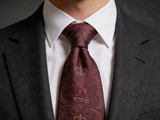 The Sovereign Crown & Crest Tie worn in a four-in-hand knot with a white collar and charcoal suit