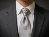 Sovereign Silver Rosette Tie worn in a four-in-hand knot with a white collar and charcoal suit