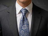 Floral Brocade Navy & Silver Tie worn in a four-in-hand knot with a white collar and charcoal suit