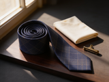 Glenurquhart Gold Windowpane Tie coiled on dark walnut with a pocket square and brass collar bar
